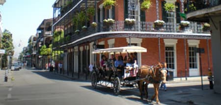 Horse-drawn carriage carrying tourists through a historic street in New Orleans.