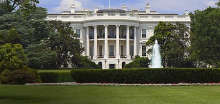 The White House, a grand white building, with a fountain and lush green lawn.