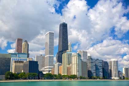 Chicago skyline with tall skyscrapers along Lake Michigan under a cloudy blue sky.